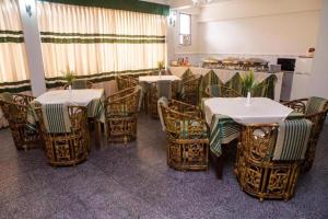 a dining room with tables and chairs and a kitchen at Meridian Hotel & Restaurant in Chittagong