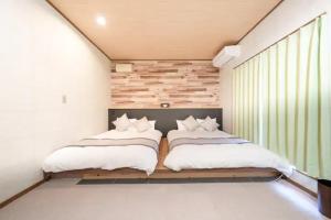 two beds in a small bedroom with a window at Kawaguchi Asama Jinjakan - Diamond Yu in Azagawa