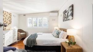 a white bedroom with a bed and a window at Beach Bungalow in Corlette