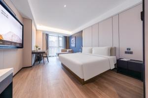 una camera da letto con un grande letto bianco e una scrivania di Atour Hotel Guiyang Convention & Exhibition City Yue Ran Plaza a Guiyang