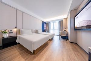 una camera d'albergo con due letti e una TV a schermo piatto di Atour Hotel Guiyang Convention & Exhibition City Yue Ran Plaza a Guiyang
