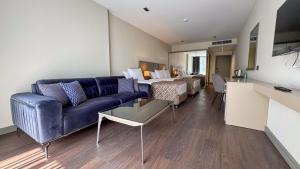 un salon avec un canapé bleu et un lit dans l'établissement Alice Hotel Antalya, à Lara