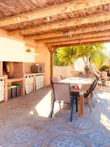 patio con tavolo e sedie sotto un pergolato in legno di La Villa a Sant Jaume d'Enveja