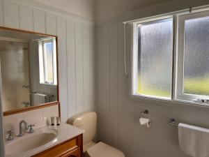 Un baño con lavabo, inodoro y ventana. en Nest - charming, comfortable coastal villa, en Port Fairy