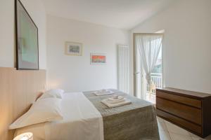 a white bedroom with a bed and a window at Casa al Cor Apartments in Nago-Torbole