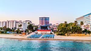 a group of blue chairs on a beach with a building at Granada Luxury Red Adult Only in Alanya