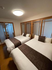 two beds in a room with windows at Ecol Beppu in Beppu