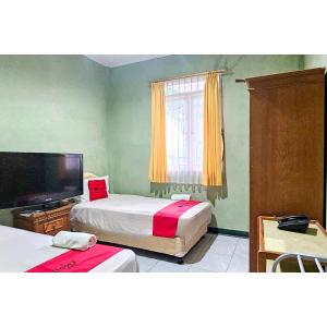 a bedroom with two beds and a flat screen tv at RedDoorz at Linggarjati Kuningan in Kuningan