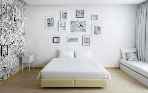a white bedroom with a bed and a couch at Beat Hotel Bangkok in Bangkok