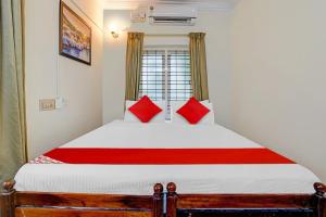 a bedroom with a large bed with red pillows at Hotel O Le Fort in Trivandrum