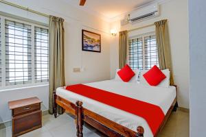 a bedroom with a large bed with red pillows at Hotel O Le Fort in Trivandrum