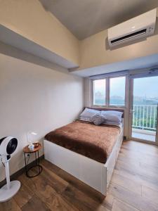 a bedroom with a bed and a large window at Pet & WFH Friendly Home Near BGC in Manila