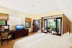 a bedroom with a large white bed and a television at Diamond Bay Resort & Spa in Nha Trang