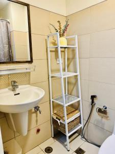 ein Badezimmer mit einem weißen Regal neben einem Waschbecken in der Unterkunft Aiya's Cozy Staycation in Tagaytay SMDC Wind in Tagaytay