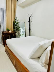 ein Bett mit weißen Laken und Kissen in einem Schlafzimmer in der Unterkunft Aiya's Cozy Staycation in Tagaytay SMDC Wind in Tagaytay