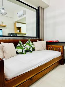 ein Holzbett mit Kissen in einem Zimmer in der Unterkunft Aiya's Cozy Staycation in Tagaytay SMDC Wind in Tagaytay