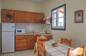 a kitchen with a table and a white refrigerator at Jasmine Apartments in Sidari