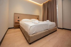 a bedroom with a large bed with white sheets and pillows at Calma Boutique Hotel in Vlorë