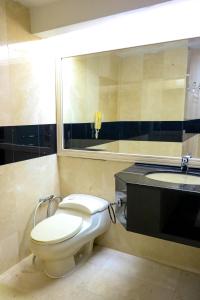 a bathroom with a toilet and a sink and a mirror at Merdeka Palace Hotel & Suites in Kuching
