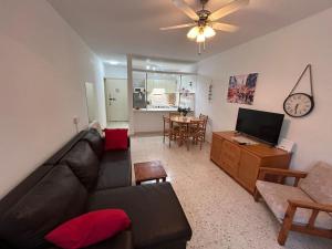 a living room with a couch and a table with a clock at Seaview apartment with garden & pool in Paphos City