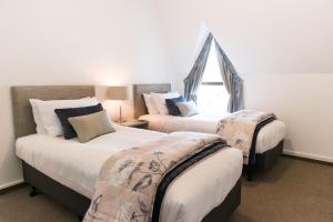 two beds in a room with a window at Aria on Bank in Dunedin