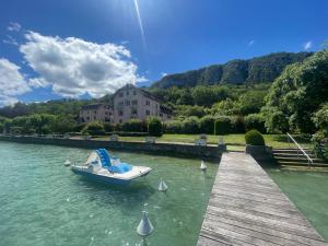 a boat sitting on the water next to a dock at Rare 2 bedroom with private beach on Lake Annecy in Doussard