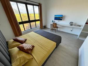 una camera da letto con un letto, una scrivania e una finestra di J'Vais Residence by SOV a Flic-en-Flac