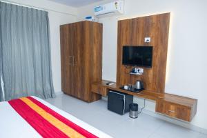 a bedroom with a bed and a tv and wooden cabinets at Ishwerya Suites in Bangalore