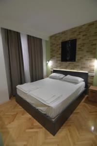 a large bed in a bedroom with a brick wall at Station 44 Apartments in Bitola