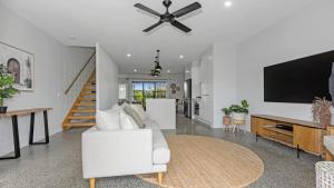 Una sala de estar con un sofá blanco y un televisor de pantalla plana. en Sea Spray by Kingscliff Accommodation, en Kingscliff