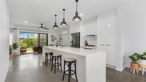 una cocina con encimera blanca y taburetes de bar en Sea Spray by Kingscliff Accommodation, en Kingscliff