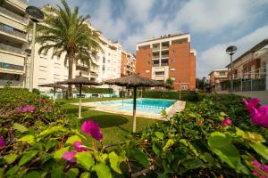 a swimming pool with two umbrellas and some flowers at MD Malva Valterna in Paterna