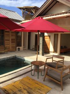 a patio with a red umbrella and chairs next to a pool at La Boheme Mini in Gili Trawangan