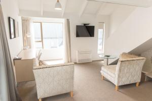 a living room with two chairs and a table at Aria on Bank in Dunedin