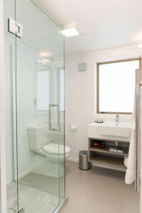 a bathroom with a glass shower and a toilet and a sink at Aria on Bank in Dunedin