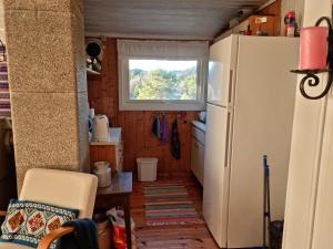 a small kitchen with a refrigerator and a window at Flott feriehus Søgne in Kristiansand