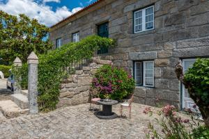 una casa in pietra con un tavolo e sedie di fronte di Quinta do Carvalhal Alojamento, Penafiel a Irivo