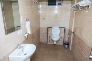 a bathroom with a white toilet and a sink at Ishwerya Suites in Bengaluru