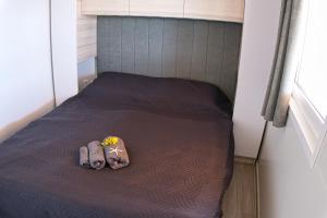 a small bed with two shoes and flowers on it at Mobilehome Palema 16 in Drage