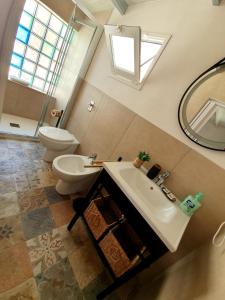 ein Badezimmer mit Waschbecken, Toilette und Spiegel in der Unterkunft Il Nido di Frisella in Marsala