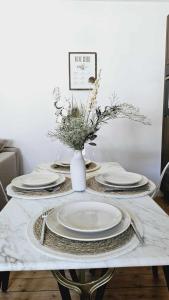 a table with plates and a vase with flowers on it at La maison du Pays d'Auge in Troarn