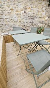 a group of tables and chairs in front of a stone wall at La maison du Pays d'Auge in Troarn