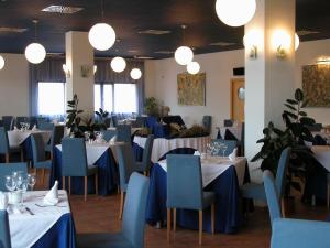 a dining room with white tables and blue chairs at Hotel Villa de Estercuel in Estercuel