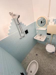 a blue tiled bathroom with a toilet and a sink at Hotel Serafini in Rimini