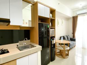 a kitchen with a black refrigerator and a table at Best Homey 1BR at 25th Floor Vasanta Innopark Apartment By Travelio in Cikarang