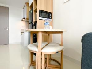 a small kitchen with a table and two stools at Best Homey 1BR at 25th Floor Vasanta Innopark Apartment By Travelio in Cikarang +8 photos