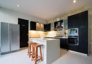 a kitchen with black cabinets and a refrigerator at 20 off Special Brilliant Location in Seminyak