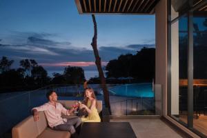 a man and a woman sitting on a balcony with drinks at Perhentian Marriott Resort & Spa in Perhentian Islands