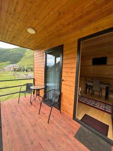 a wooden deck with a table and chairs on it at Quiet cottage, Stepantsminda, Achkhoti in Ach'khoti +5 photos