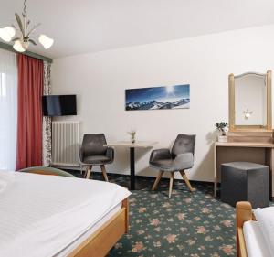 a hotel room with a bed and two chairs and a table at Hotel Bergglück in Filzmoos